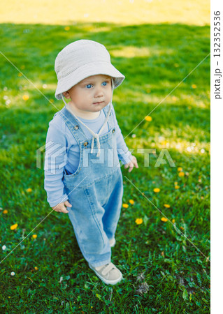 Cute boy running on the grass in a stylish shirt and sunbathing in the sun. Carefree childhood with joyful laughter of a child. Toddler having fun and enjoying a walk in nature. Cute boy running on the grass in a stylish shirt and sunbathing in the sun. Carefree childhood with joyful laughter of a child. Toddler having fun and enjoying a walk in nature. 132352536