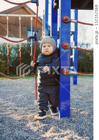 Happy toddler boy on a walk on the playground. Child development, healthy lifestyle of the child. Boy outdoors on an autumn walk. Happy toddler boy on a walk on the playground. Child development, healthy lifestyle of the child. Boy outdoors on an autumn walk. 132352569