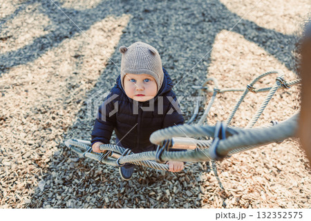 Happy toddler boy on a walk on the playground. Child development, healthy lifestyle of the child. Boy outdoors on an autumn walk. Happy toddler boy on a walk on the playground. Child development, healthy lifestyle of the child. Boy outdoors on an autumn walk. 132352575