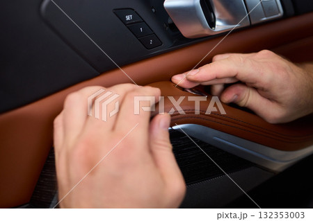 Skilled hands install a car door handle trim, highlighting craftsmanship and precision in design 132353003