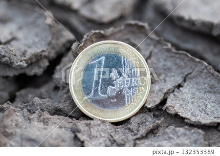 1 euro coin lying in cracked dry earth. A single euro coin resting in cracked, dry ground, symbolizing economic tension, instability in Europe 1 euro coin lying in cracked dry earth. A single euro coin resting in cracked, dry ground, symbolizing economic tension, instability in Europe 132353389