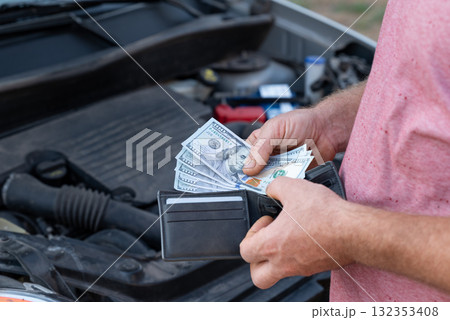 Customer taking dollar banknotes of his wallet to pay for car repair. Spending money for repair at car service, high price for spare parts and fixing Customer taking dollar banknotes of his wallet to pay for car repair. Spending money for repair at car service, high price for spare parts and fixing 132353408