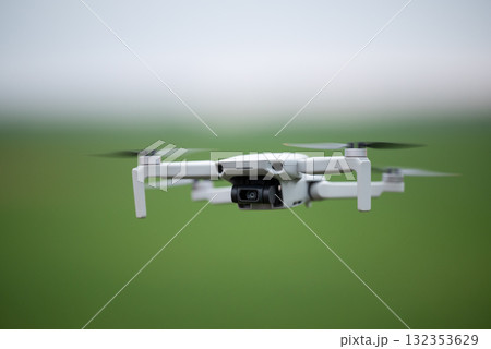 Drone hovering in the air, close up. Quadcopter on green summer background, modern equipment concept 132353629