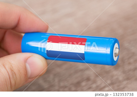 Rechargeable li-ion battery in hand of a man with sticker of Netherlands flag. Produce lithium batteries in Netherlands Rechargeable li-ion battery in hand of a man with sticker of Netherlands flag. Produce lithium batteries in Netherlands 132353738