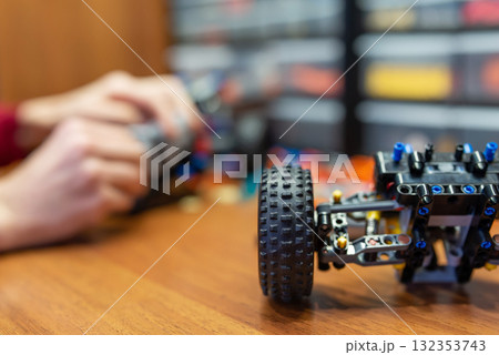 Close up of a machine toy part made of engineering constructor on the table. Kid playing with developing mechanics constructor kit, creates different mechanisms 132353743