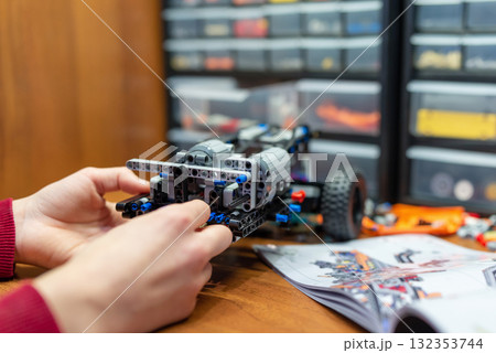 Kid making robot toy car following the instructions. Boy playing with developing kit for young engineers Kid making robot toy car following the instructions. Boy playing with developing kit for young engineers 132353744