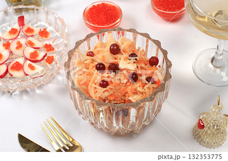 Festive Christmas and New Year's dishes on an elegant table. Vegetarian appetizers of sauerkraut with cranberries, radish, cucumber, egg, and olive salad, red caviar, and glasses of champagne Festive Christmas and New Year's dishes on an elegant table. Vegetarian appetizers of sauerkraut with cranberries, radish, cucumber, egg, and olive salad, red caviar, and glasses of champagne 132353775