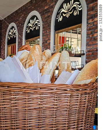 Close-up of a woven wicker basket with fresh baguettes sticking out. Perfect for bakery, food, lifestyle, and rustic concepts. Close-up of a woven wicker basket with fresh baguettes sticking out. Perfect for bakery, food, lifestyle, and rustic concepts. 132353889