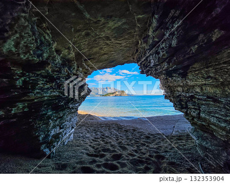 Entrance of a seaside cave frames the Adriatic Sea with Hawaii Island in the distance near Budva, Montenegro. Peaceful marine landscape. 132353904