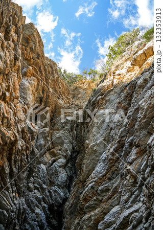 View from the base of a stone cliff looking upward toward cloudy sky. Dramatic natural landscape scene. View from the base of a stone cliff looking upward toward cloudy sky. Dramatic natural landscape scene. 132353913