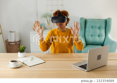 African American young woman wearing using virtual reality metaverse VR glasses headset at home. Girl touching air during VR experience on virtual reality helmet. Simulation hi-tech videogame concept African American young woman wearing using virtual reality metaverse VR glasses headset at home. Girl touching air during VR experience on virtual reality helmet. Simulation hi-tech videogame concept 132354089