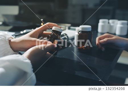Female doctor holding a medicine bottle is checking the quality of medicine for any side effects the patient or not and recording patient information at the hospital. medical and health care concept 132354208