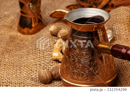 Shiny copper turk with brewed coffee on brown wooden table 132354299