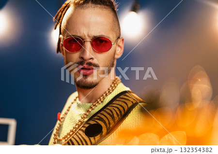 Young fashionable man in pink sunglasses playing guitar with joy Young fashionable man in pink sunglasses playing guitar with joy 132354382