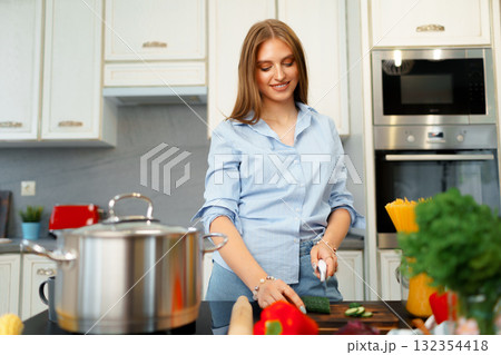 Young woman cutting vegetables for salad in kitchen Young woman cutting vegetables for salad in kitchen 132354418
