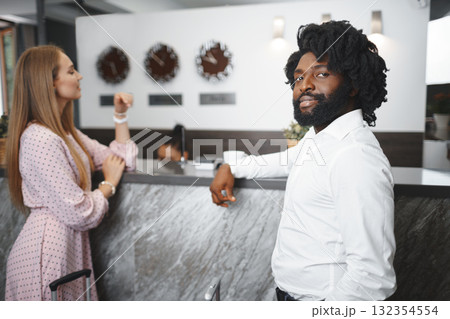 Business trip concept. Black man and caucasian woman businesspeople colleagues checking-in in hotel Business trip concept. Black man and caucasian woman businesspeople colleagues checking-in in hotel 132354554