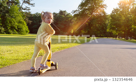 Child riding. Scooter toddler park play. Summer road motion casual sport. 132354646