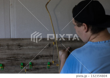Man installing wood-effect ceramic tiles on a wall, meticulously adjusting their position during a home interior renovation, representing diy enthusiasm and skilled craftsmanship. 132354804