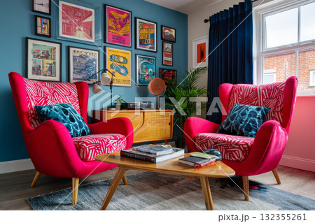 A pair of red upholstered chairs with a tropical print cushion and throw pillow in front of colorful framed posters on blue walls A pair of red upholstered chairs with a tropical print cushion and throw pillow in front of colorful framed posters on blue walls 132355261