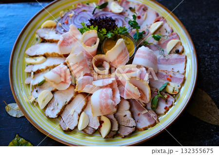 meat plate set Cold smoked meat plate with prosciutto, salami, bacon, pork chops, cheese and olives on gray stone background. From top view meat plate set Cold smoked meat plate with prosciutto, salami, bacon, pork chops, cheese and olives on gray stone background. From top view 132355675