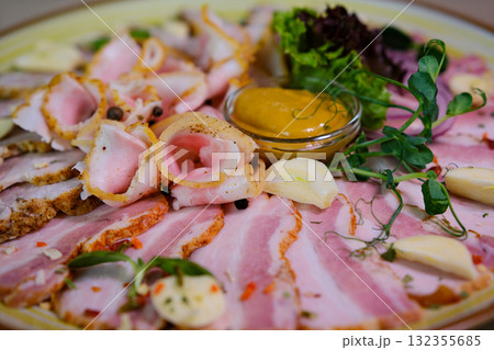 Assorted cold cuts (ham, turkey, sausage) arranged on a plate and garnished with fresh parsley leaves. 132355685