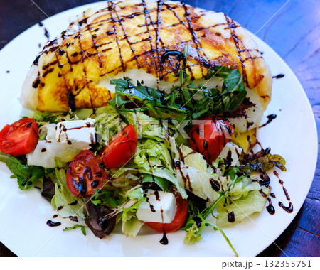 protein omelet salad bacon and green salad top view. Top view of an omelet with bacon and fresh greens on a black plate. 132355751