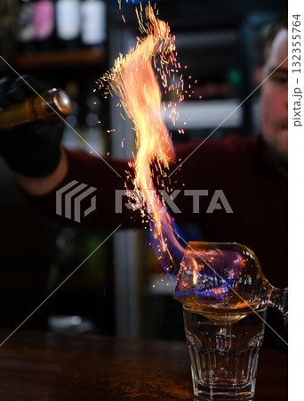 Bartender making a fire flame cocktail in a elegant night club party unique experience.  132355764
