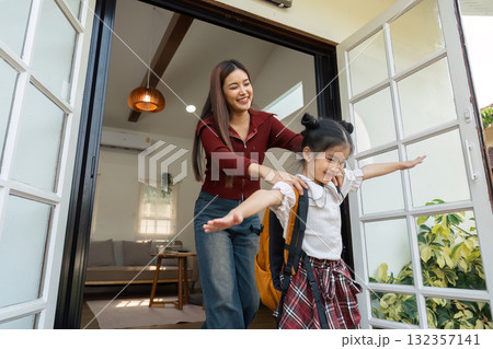 Excitement and Anticipation. A mother joyously sends her daughter off to school with encouragement. Excitement and Anticipation. A mother joyously sends her daughter off to school with encouragement. 132357141