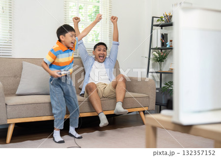 Family Fun and Gaming. A father and son celebrate a gaming victory together on the couch. Family Fun and Gaming. A father and son celebrate a gaming victory together on the couch. 132357152