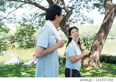 Wellness and Senior Joy. A senior couple sharing laughter while jogging in a park. 132357168