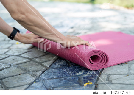 Wellness in Yoga: Senior preparing yoga mat outdoors 132357169