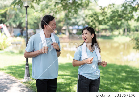 Wellness and Senior Fitness. A joyful senior couple enjoying a morning walk in the park, promoting health and happiness. 132357170