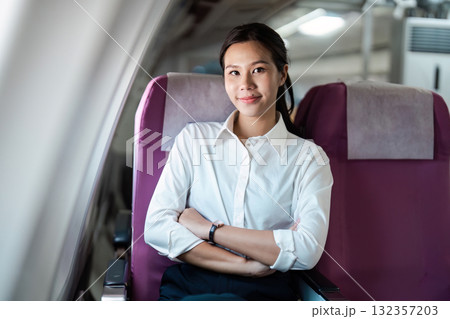Business travel: Young woman smiling and relaxing in airplane seat Business travel: Young woman smiling and relaxing in airplane seat 132357203