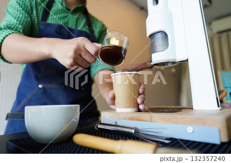 Barista Skills and Craftsmanship. A skilled barista prepares fresh coffee in an eco-friendly cafe environment. 132357240