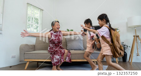 Excitement and Family Reunion. Grandmother joyfully welcomes her granddaughters as they rush to her with open arms. 132357250