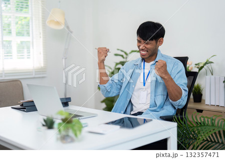Businessman celebrating success at home office with laptop 132357471