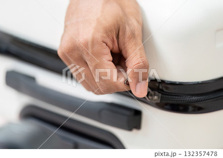 Zipping Up and Finalizing Luggage. A close-up of a hand zipping a suitcase, ready for the travel adventure ahead. 132357478