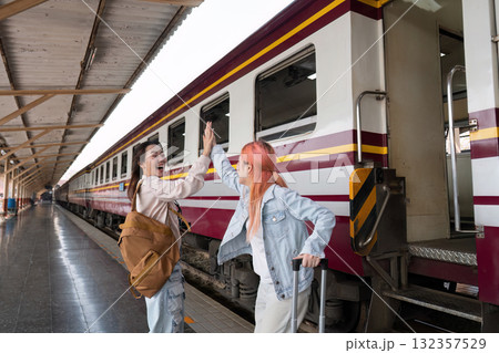 Connection and Celebration. Friends share a high-five at the train station, celebrating their adventure. 132357529