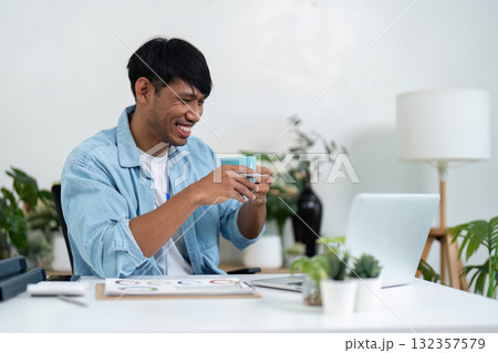 Remote Work and Sustainability. A young professional enjoying a coffee break while working from home in a green environment. Remote Work and Sustainability. A young professional enjoying a coffee break while working from home in a green environment. 132357579