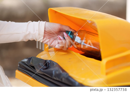 Recycling and Waste Management. An individual disposing of a plastic bottle in a recycling bin, contributing to environmental sustainability. 132357738