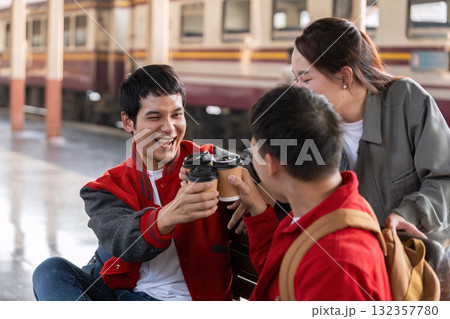 Cheers and Togetherness. Friends toast with coffee cups while waiting for their train, celebrating their journey. 132357780