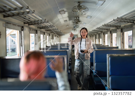 Exploration and Experience. A young woman waves excitedly in an empty train car, ready for her next adventure. 132357782