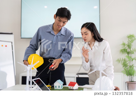 Sustainability and Engineering Collaboration. Engineers discussing sustainable housing solutions with miniature models. 132357818