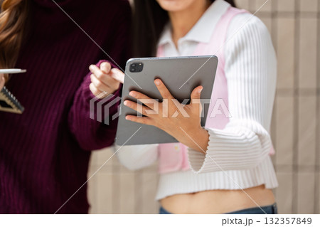 Study Practices and Technology. Students engaged in coursework discussion, utilizing a tablet for research. Study Practices and Technology. Students engaged in coursework discussion, utilizing a tablet for research. 132357849