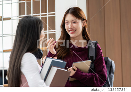Exchange and Understanding. Two students enjoy a conversation with books in hand, representing the essence of academic friendship. 132357854