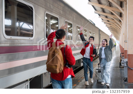 Farewell and Travel Adventure. Friends waving goodbye at a train station as they embark on a new journey. 132357959