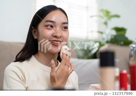 Skincare and Empowerment. A young woman applying foundation with a sponge to enhance her natural beauty. Skincare and Empowerment. A young woman applying foundation with a sponge to enhance her natural beauty. 132357990