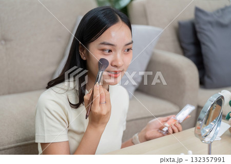 Skincare and Empowerment. Woman applying blush with a brush showcasing her beauty. Skincare and Empowerment. Woman applying blush with a brush showcasing her beauty. 132357991