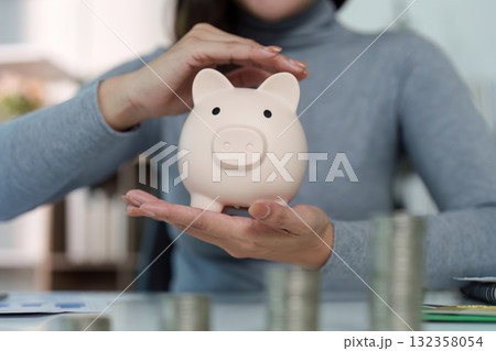 Financial Awareness. Woman protecting piggy bank while managing savings. Financial Awareness. Woman protecting piggy bank while managing savings. 132358054