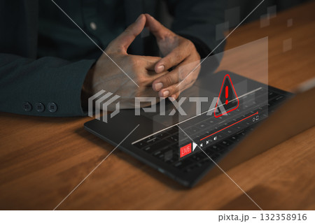User using a laptop computer with a glowing warning error icon and live stream interface, symbolizing cyber security alert, system error, online risk, technology problem and digital safety. User using a laptop computer with a glowing warning error icon and live stream interface, symbolizing cyber security alert, system error, online risk, technology problem and digital safety. 132358916